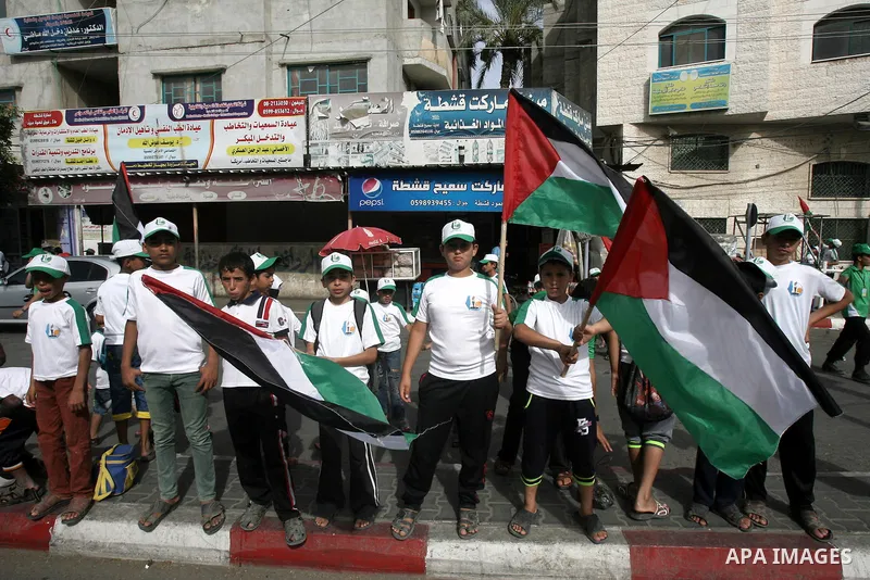 Palestinian children who participate in a summer camp organized by Hamas, wave their national flags as they parade the streets during a rally to show solidarity with Palestinian prisoners held in Israeli jails, in Rafah...
