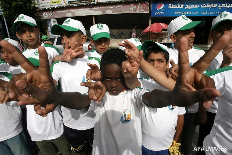 Palestinian children who participate in a summer camp organized by Hamas, flash victory signs as they parade the streets during a rally to show solidarity with Palestinian prisoners held in Israeli jails, in Rafah in the...