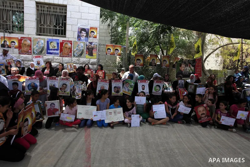 Palestinians hold prisoners pictures who held in Israeli jails during a protest to show solidarity with prisoners on hunger strike, outside the Red Cross headquarter in the West Bank City of Ramallah, June 03, 2014. Abou...