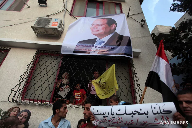 Members of Egyptian community in the Gaza Strip hold Egyptian flags and pictures of ex-army chief Abdel Fattah al-Sisi as they celebrate after Sisi scored a crushing presidential election triumph, in Gaza City on June 03...