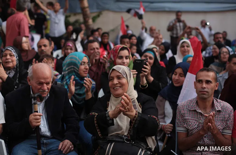 Members of Egyptian community in the Gaza Strip hold Egyptian flags and pictures of ex-army chief Abdel Fattah al-Sisi as they celebrate after Sisi scored a crushing presidential election triumph, in Gaza City on June 03...