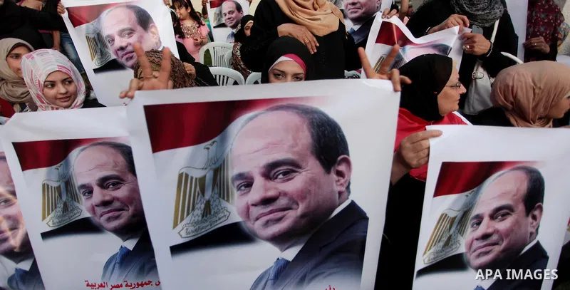 Members of Egyptian community in the Gaza Strip hold Egyptian flags and pictures of ex-army chief Abdel Fattah al-Sisi as they celebrate after Sisi scored a crushing presidential election triumph, in Gaza City on June 03...
