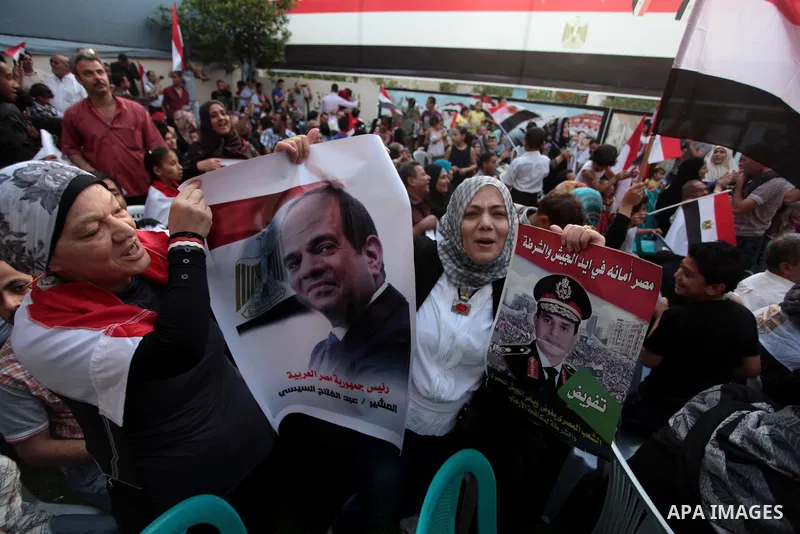 Members of Egyptian community in the Gaza Strip hold Egyptian flags and pictures of ex-army chief Abdel Fattah al-Sisi as they celebrate after Sisi scored a crushing presidential election triumph, in Gaza City on June 03...