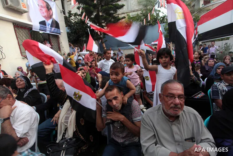 Members of Egyptian community in the Gaza Strip hold Egyptian flags and pictures of ex-army chief Abdel Fattah al-Sisi as they celebrate after Sisi scored a crushing presidential election triumph, in Gaza City on June 03...