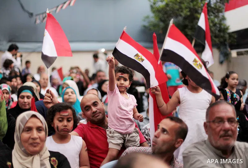 Members of Egyptian community in the Gaza Strip hold Egyptian flags and pictures of ex-army chief Abdel Fattah al-Sisi as they celebrate after Sisi scored a crushing presidential election triumph, in Gaza City on June 03...