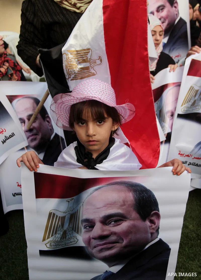 Members of Egyptian community in the Gaza Strip hold Egyptian flags and pictures of ex-army chief Abdel Fattah al-Sisi as they celebrate after Sisi scored a crushing presidential election triumph, in Gaza City on June 03...