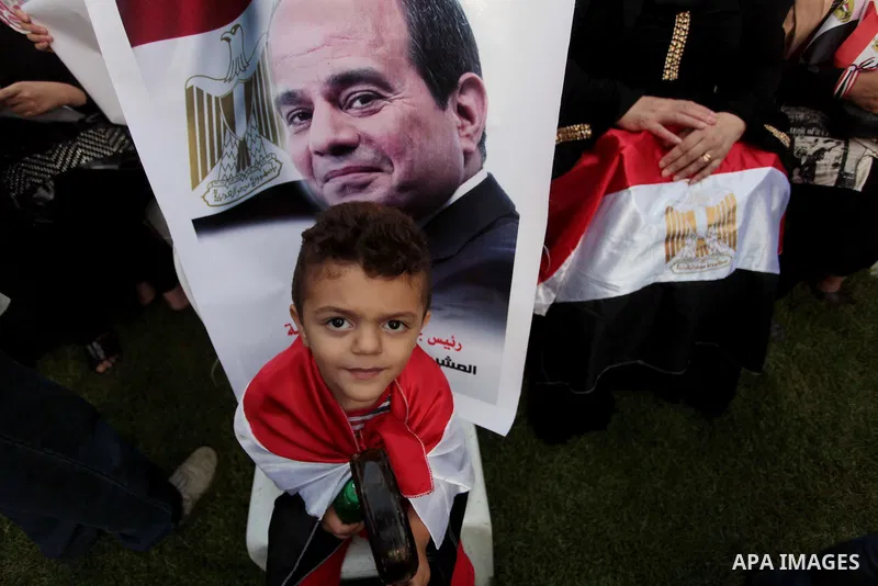 Members of Egyptian community in the Gaza Strip hold Egyptian flags and pictures of ex-army chief Abdel Fattah al-Sisi as they celebrate after Sisi scored a crushing presidential election triumph, in Gaza City on June 03...