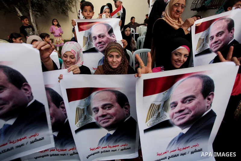 Members of Egyptian community in the Gaza Strip hold Egyptian flags and pictures of ex-army chief Abdel Fattah al-Sisi as they celebrate after Sisi scored a crushing presidential election triumph, in Gaza City on June 03...