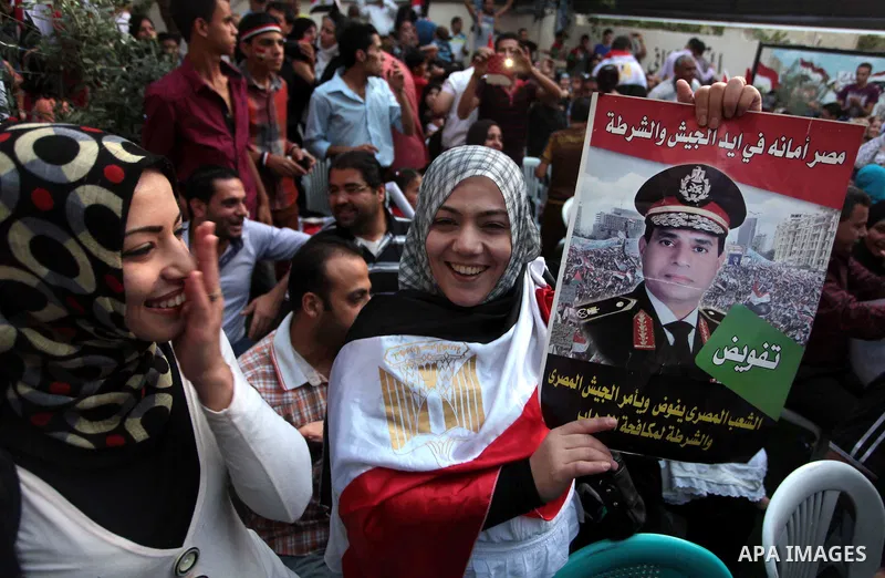 Members of Egyptian community in the Gaza Strip hold Egyptian flags and pictures of ex-army chief Abdel Fattah al-Sisi as they celebrate after Sisi scored a crushing presidential election triumph, in Gaza City on June 03...