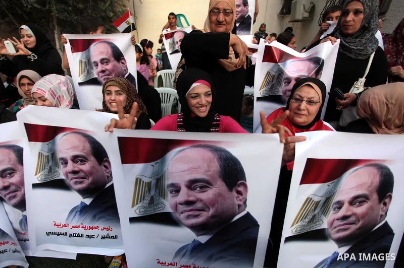 Members of Egyptian community in the Gaza Strip hold Egyptian flags and pictures of ex-army chief Abdel Fattah al-Sisi as they celebrate after Sisi scored a crushing presidential election triumph, in Gaza City on June 03...
