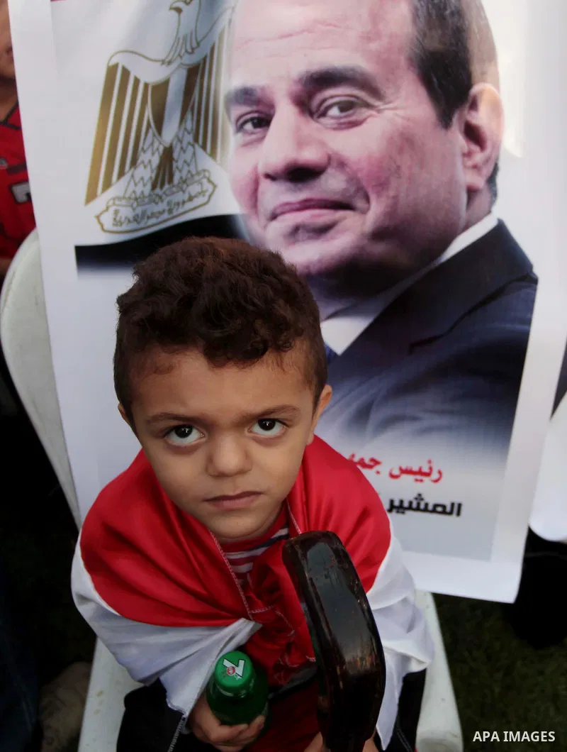 Members of Egyptian community in the Gaza Strip hold Egyptian flags and pictures of ex-army chief Abdel Fattah al-Sisi as they celebrate after Sisi scored a crushing presidential election triumph, in Gaza City on June 03...