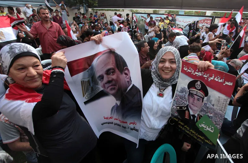 Members of Egyptian community in the Gaza Strip hold Egyptian flags and pictures of ex-army chief Abdel Fattah al-Sisi as they celebrate after Sisi scored a crushing presidential election triumph, in Gaza City on June 03...