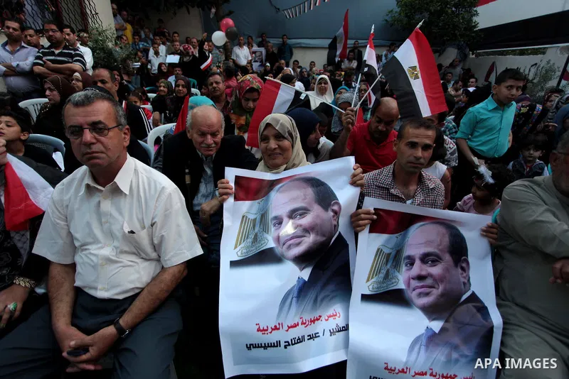Members of Egyptian community in the Gaza Strip hold Egyptian flags and pictures of ex-army chief Abdel Fattah al-Sisi as they celebrate after Sisi scored a crushing presidential election triumph, in Gaza City on June 03...