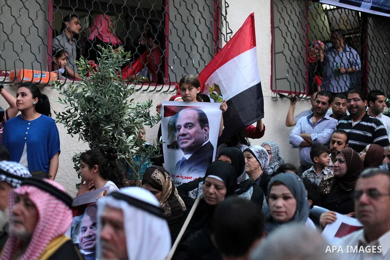 Members of Egyptian community in the Gaza Strip hold Egyptian flags and pictures of ex-army chief Abdel Fattah al-Sisi as they celebrate after Sisi scored a crushing presidential election triumph, in Gaza City on June 03...