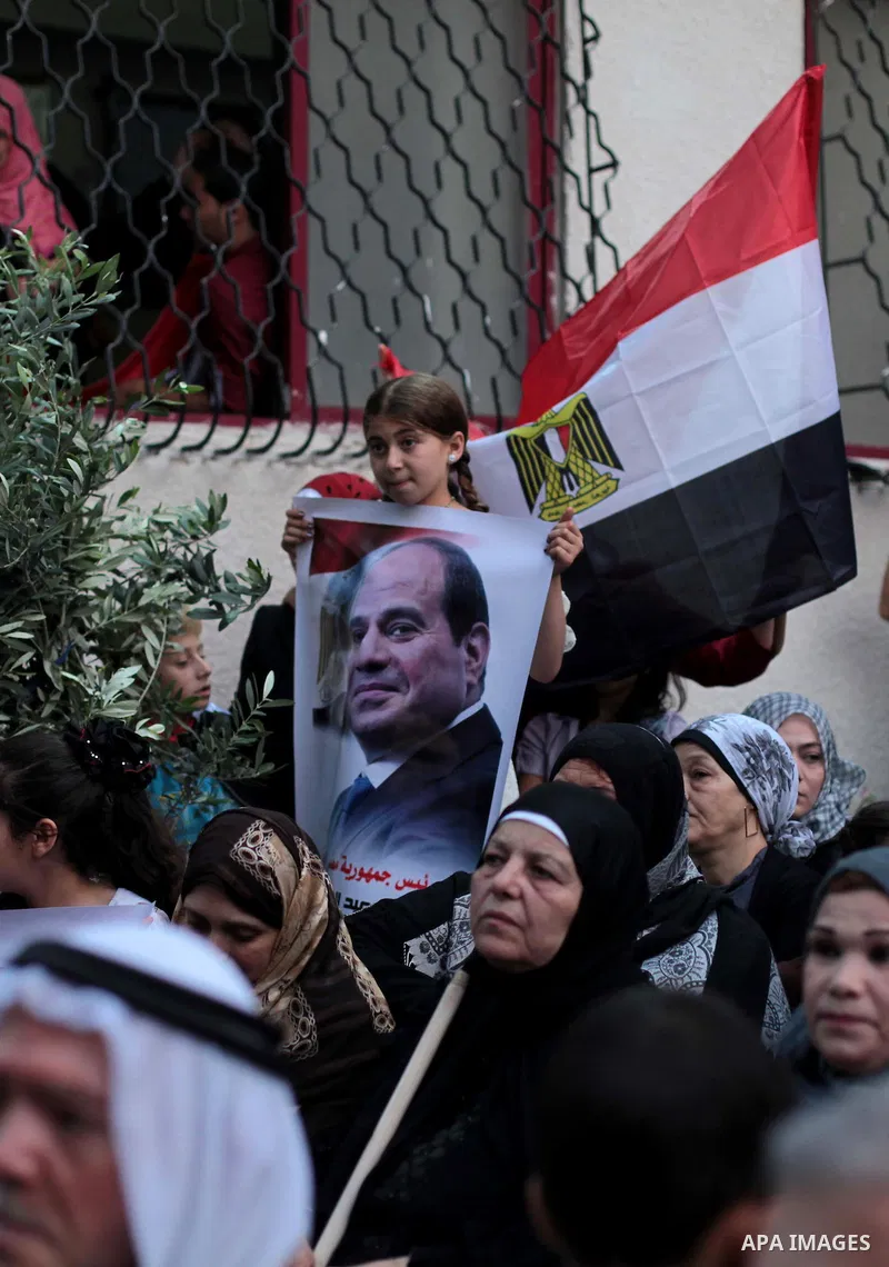 Members of Egyptian community in the Gaza Strip hold Egyptian flags and pictures of ex-army chief Abdel Fattah al-Sisi as they celebrate after Sisi scored a crushing presidential election triumph, in Gaza City on June 03...