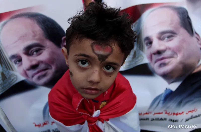 Members of Egyptian community in the Gaza Strip hold Egyptian flags and pictures of ex-army chief Abdel Fattah al-Sisi as they celebrate after Sisi scored a crushing presidential election triumph, in Gaza City on June 03...