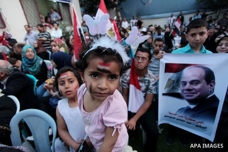 Members of Egyptian community in the Gaza Strip hold Egyptian flags and pictures of ex-army chief Abdel Fattah al-Sisi as they celebrate after Sisi scored a crushing presidential election triumph, in Gaza City on June 03...