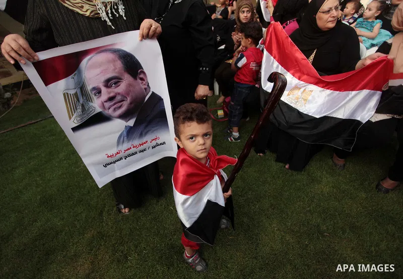 Members of Egyptian community in the Gaza Strip hold Egyptian flags and pictures of ex-army chief Abdel Fattah al-Sisi as they celebrate after Sisi scored a crushing presidential election triumph, in Gaza City on June 03...