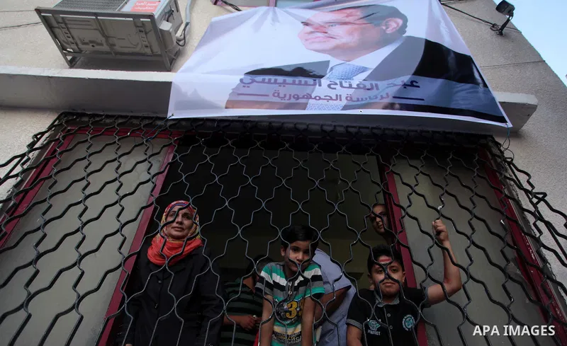 Members of Egyptian community in the Gaza Strip hold Egyptian flags and pictures of ex-army chief Abdel Fattah al-Sisi as they celebrate after Sisi scored a crushing presidential election triumph, in Gaza City on June 03...