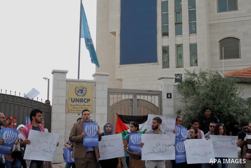 Palestinian activists hold banners during a protest outside the headquarters of the United Nations (UNRCP) in the West Bank city of Ramallah, on June 04, 2014. Protesters closed the doors of the office during a protest t...