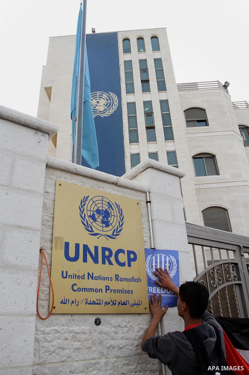 Palestinian activists hold banners during a protest outside the headquarters of the United Nations (UNRCP) in the West Bank city of Ramallah, on June 04, 2014. Protesters closed the doors of the office during a protest t...