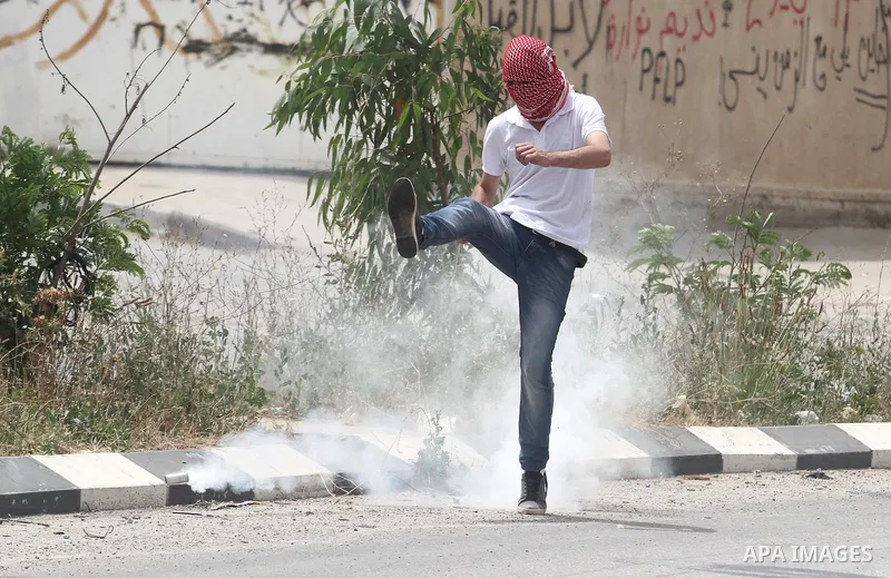 A Palestinian protester kicks back a tear gas canister during clashes with Israeli soldiers after a protest in support of Palestinian prisoners hunger striking since 42 days in Israeli jails, outside Ofer, an Israeli mil...