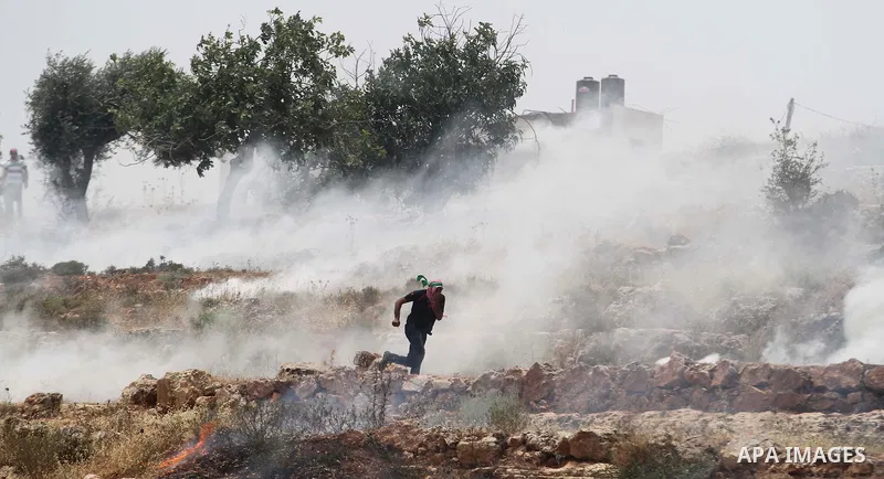 A Palestinian runs from tear gas during clashes with Israeli soldiers after a protest in support of Palestinian prisoners hunger striking since 42 days in Israeli jails, outside Ofer, an Israeli military prison near the...
