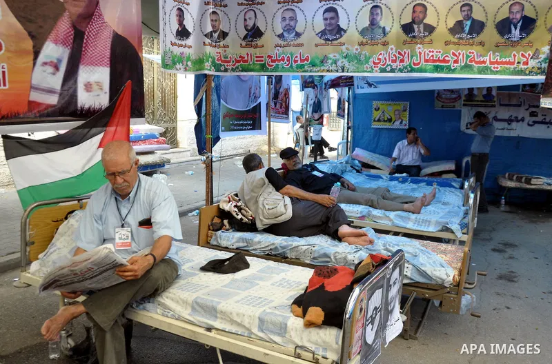 A Palestinian man sits under a tent in front of the Red Crescent offices in Gaza City on June 4, 2014 after he stopped eating in solidarity with 125 prisoners on long-term hunger strike in Israeli jails. Most of the pris...