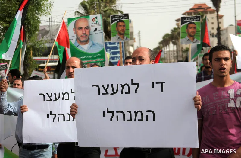 Palestinians hold national flags and posters of jailed relatives during a protest in solidarity with prisoners on hunger strike,in the West Bank city of Hebron June 4, 2014. Some 120 Palestinians jailed without trial in...