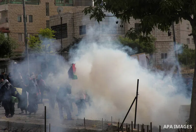 Palestinians take cover from tear gas fired by Israeli soldiers during a protest in solidarity with prisoners on hunger strike,in the West Bank city of Hebron June 4, 2014. Some 120 Palestinians jailed without trial in I...