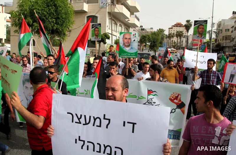 Palestinians hold national flags and posters of jailed relatives during a protest in solidarity with prisoners on hunger strike,in the West Bank city of Hebron June 4, 2014. Some 120 Palestinians jailed without trial in...
