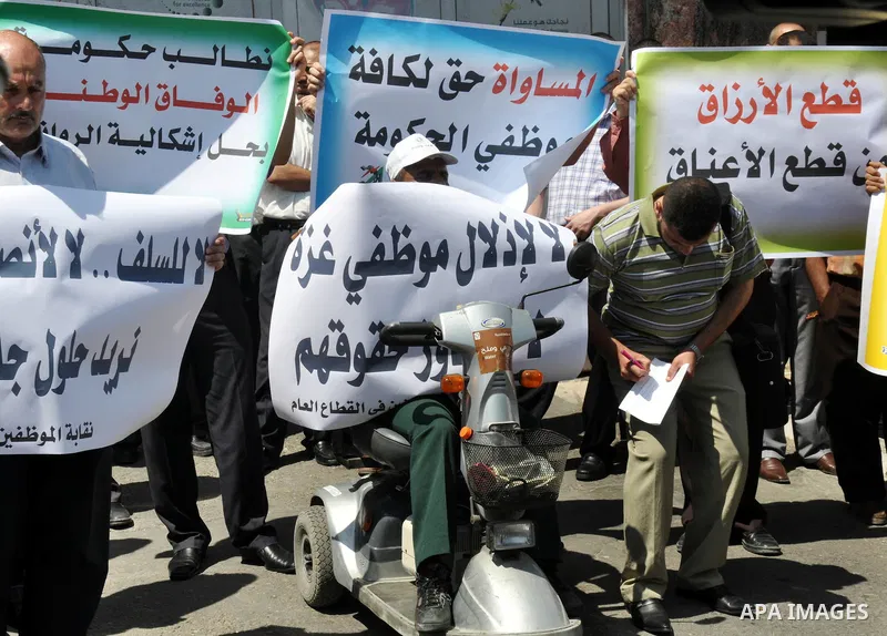 Palestinian employees of the formerly Hamas-run government in the Gaza Strip hold banners during a protest to demanding their salaries, in Gaza city, on June 09, 2014. Banks in the Gaza Strip remained closed Sunday morni...