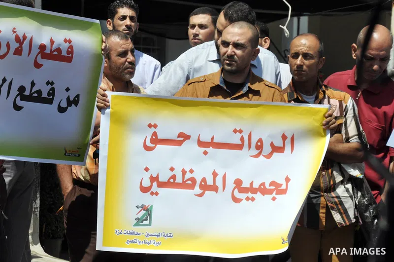 Palestinian employees of the formerly Hamas-run government in the Gaza Strip hold banners during a protest to demanding their salaries, in Gaza city, on June 09, 2014. Banks in the Gaza Strip remained closed Sunday morni...