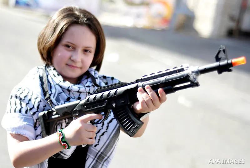 A Palestinian girl holds a toy weapon during a demonstration in support of 125 Palestinian prisoners detained in Israeli jails and who have been on hunger strike for six weeks, outside Red Cross office, in Gaza City on J...