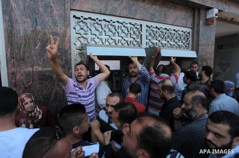 Employees paid by the Palestinian Authority wait to receive their salaries outside a bank after a scuffle with employees appointed by Hamas since 2007, in Gaza City on June 11, 2014. Gaza's banks reopened Wednesday after...