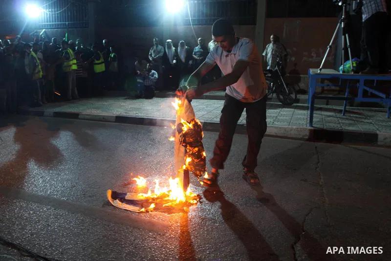 Palestinian supporters of the Hamas movement burn an Israeli flag during a demonstration against the political arrests and the violence against Hamas members by PA security in the West Bank, in Gaza City on June 11, 2014...