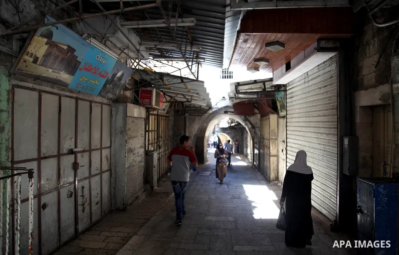 People walk past closed shops in Jerusalem's Old City June 12, 2014. Shops were shuttered in East Jerusalem on Thursday to show solidarity with hundreds of Palestinian prisoners in Israeli jails who have joined a hunger...