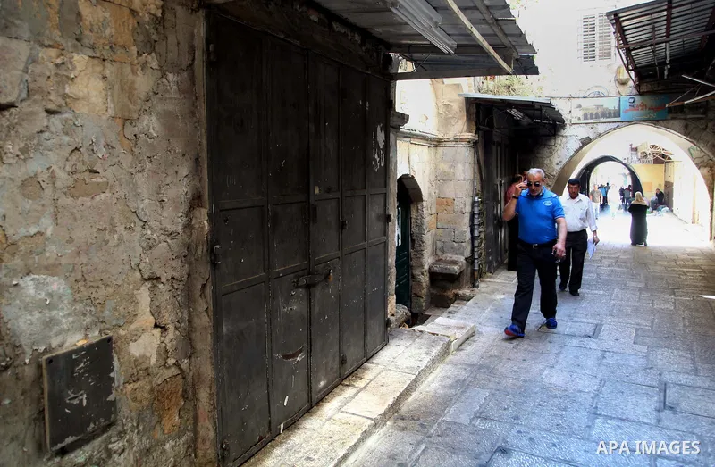 People walk past closed shops in Jerusalem's Old City June 12, 2014. Shops were shuttered in East Jerusalem on Thursday to show solidarity with hundreds of Palestinian prisoners in Israeli jails who have joined a hunger...