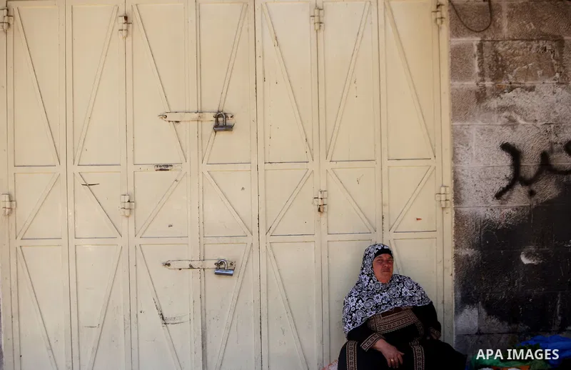 A Palestinian woman sits in front of closed shops in Jerusalem's Old City June 12, 2014. Shops were shuttered in East Jerusalem on Thursday to show solidarity with hundreds of Palestinian prisoners in Israeli jails who h...