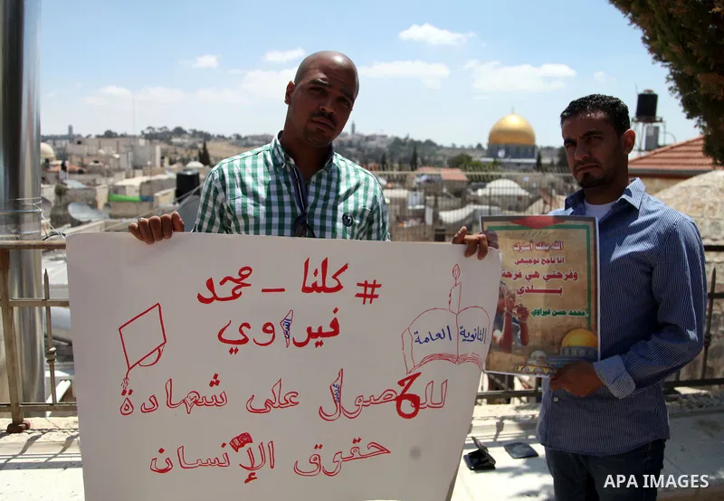 Palestinian relatives and friends of prisoner Mohammed Firawi, 17, hold placards during a protest in front the office of the Ministry of Education, in Jerusalem's Old City on June 11, 2014. Palestinians protest against t...