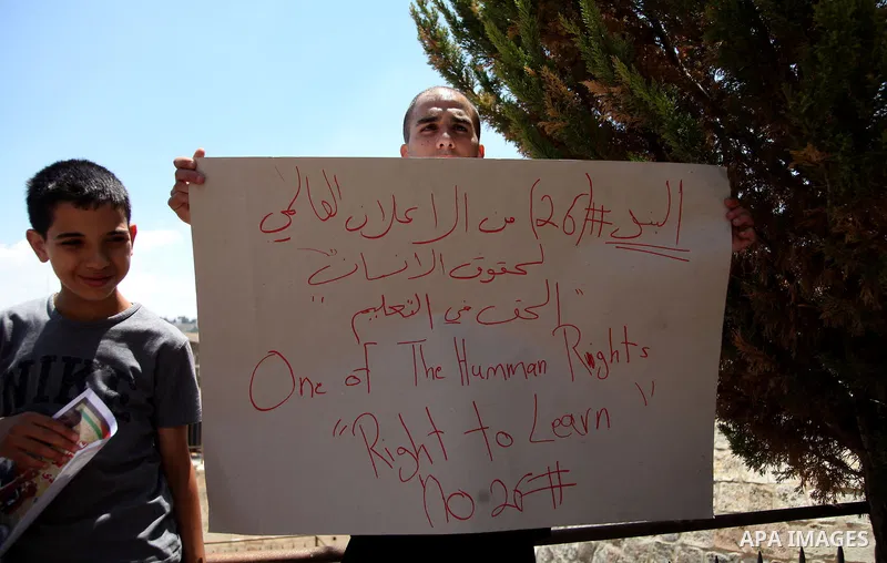 Palestinian relatives and friends of prisoner Mohammed Firawi, 17, hold placards during a protest in front the office of the Ministry of Education, in Jerusalem's Old City on June 11, 2014. Palestinians protest against t...