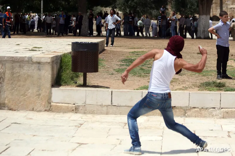 A Palestinian youth throws stones at Israeli riot police during clashes following Friday prayers at the al-Aqsa mosque compound in Jerusalem's Old City on June 13, 2014. Photo by Saeed Qaq