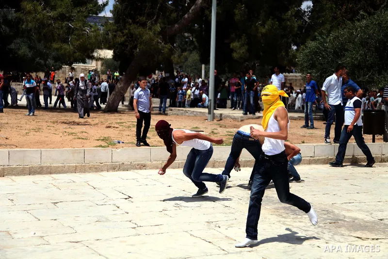 Palestinian youth throw stones at Israeli riot police during clashes following Friday prayers at the al-Aqsa mosque compound in Jerusalem's Old City on June 13, 2014. Photo by Saeed Qaq