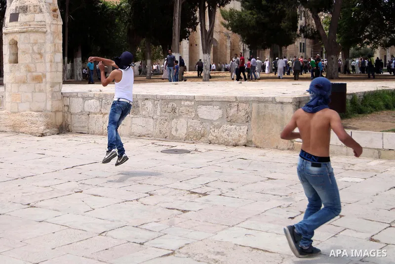 Palestinian youth throw stones at Israeli riot police during clashes following Friday prayers at the al-Aqsa mosque compound in Jerusalem's Old City on June 13, 2014. Photo by Saeed Qaq