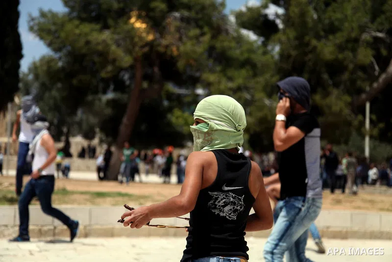 Palestinian youth throw stones at Israeli riot police during clashes following Friday prayers at the al-Aqsa mosque compound in Jerusalem's Old City on June 13, 2014. Photo by Saeed Qaq