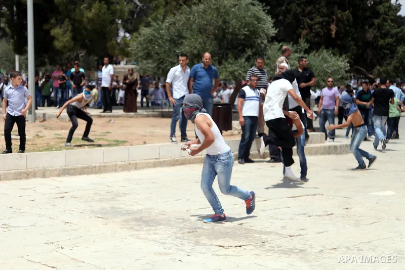Palestinian youth throw stones at Israeli riot police during clashes following Friday prayers at the al-Aqsa mosque compound in Jerusalem's Old City on June 13, 2014. Photo by Saeed Qaq