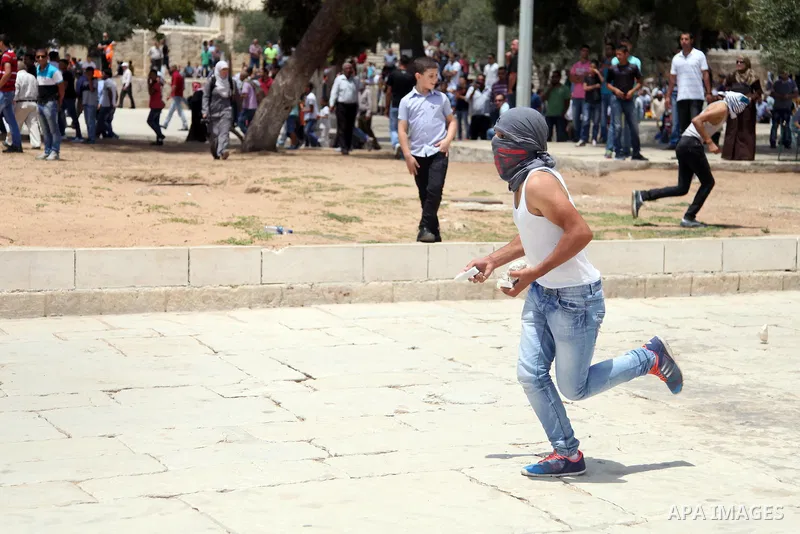 A Palestinian youth throws stones at Israeli riot police during clashes following Friday prayers at the al-Aqsa mosque compound in Jerusalem's Old City on June 13, 2014. Photo by Saeed Qaq