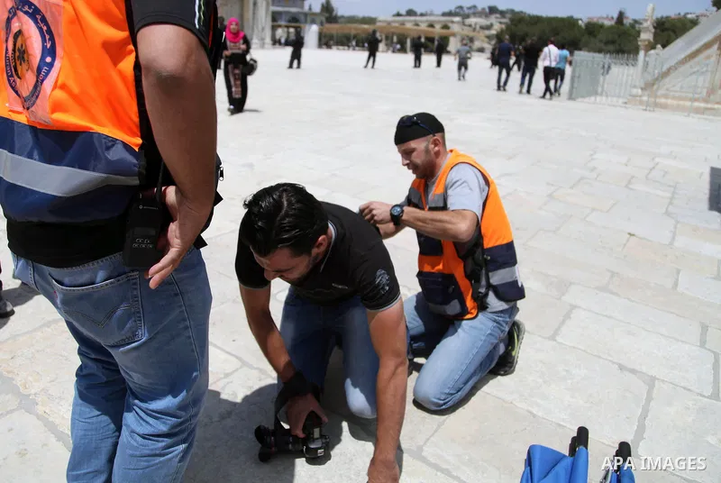 Palestinian medics treat a photographer during clashes between Palestinian youths and Israeli riot police following Friday prayers at the al-Aqsa mosque compound in Jerusalem's Old City on June 13, 2014. Photo by Saeed Q...