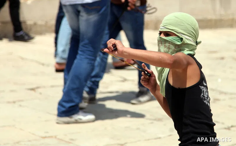 A Palestinian youth throws stones at Israeli riot police during clashes following Friday prayers at the al-Aqsa mosque compound in Jerusalem's Old City on June 13, 2014. Photo by Saeed Qaq