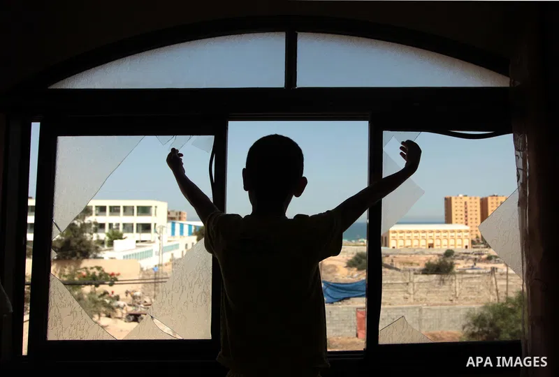 A Palestinian boy is pictured through a window following an air strike by the Israeli airforce on Gaza City, on June 16, 2014. Israel launched air strikes on different areas of on Gaza Strip, as Israeli troops killed a P...